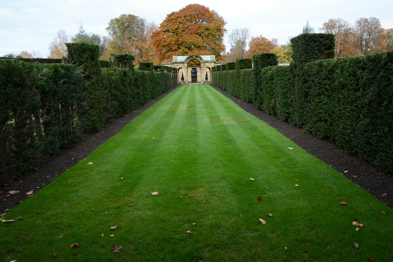 Long curving green lawn flanked by trimmed hedges, recently maintained.